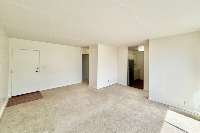 empty room featuring baseboards and light colored carpet