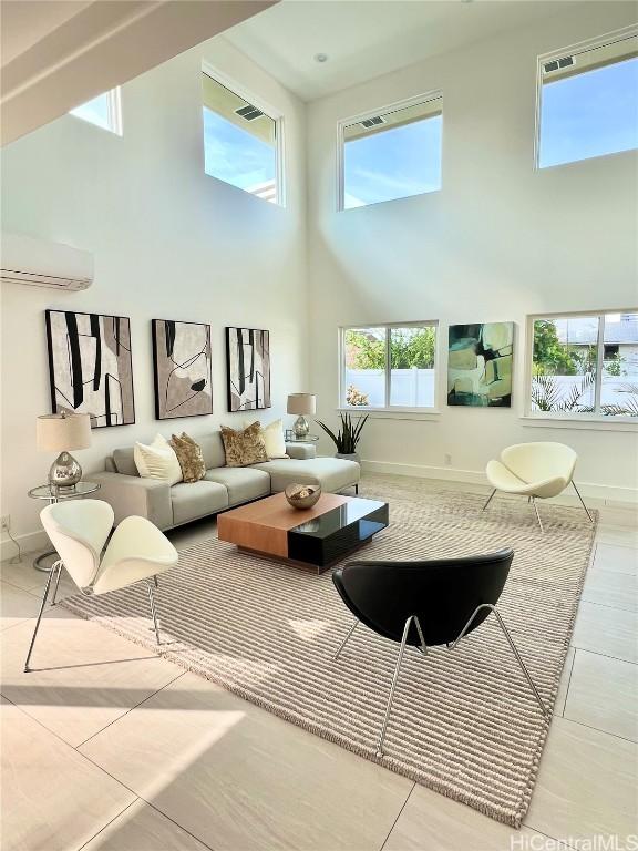 living room featuring a wall mounted AC, baseboards, and a towering ceiling
