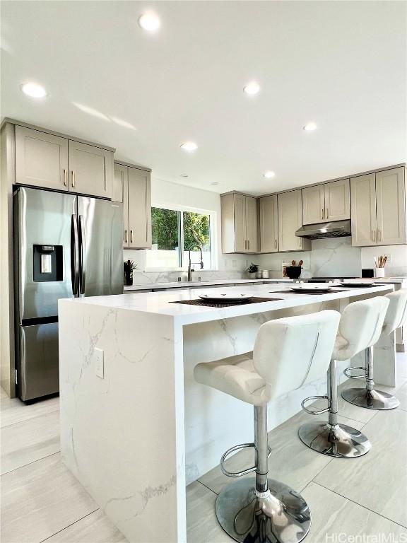 kitchen featuring light countertops, a kitchen island, stainless steel refrigerator with ice dispenser, and gray cabinetry