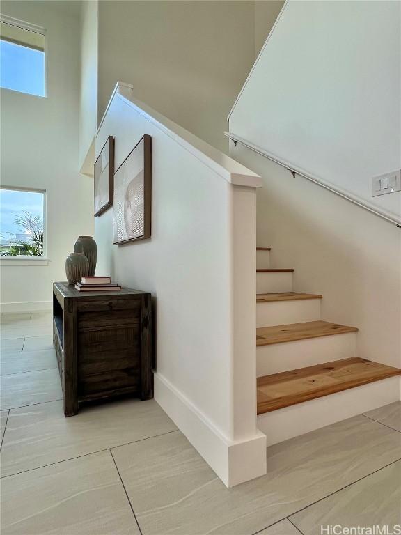 stairway with a towering ceiling, baseboards, and a wealth of natural light