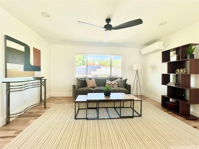 living room with baseboards, wood finished floors, an AC wall unit, and a ceiling fan