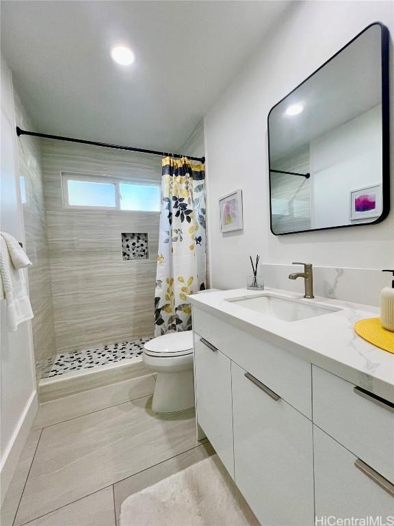 bathroom featuring a tile shower, toilet, and vanity