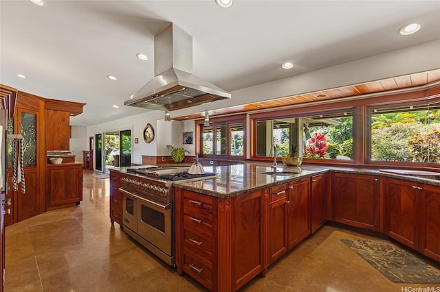 kitchen with island range hood, range with two ovens, a sink, dark stone counters, and recessed lighting