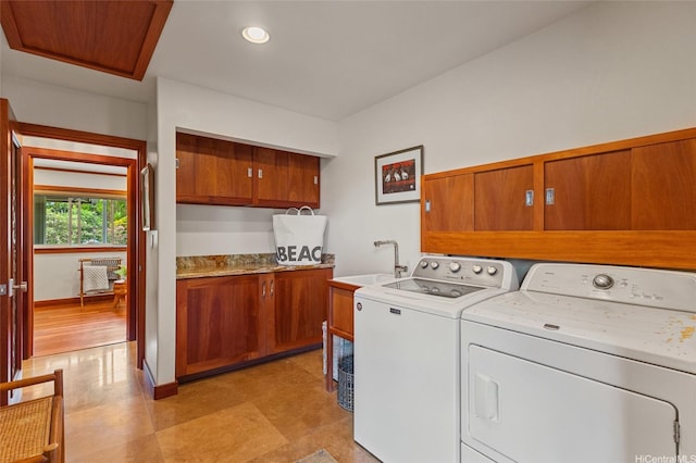 clothes washing area with a sink, light floors, cabinet space, and washer and dryer