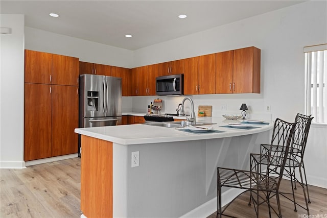 95-1023 Hehina St, Mililani, HI 96789 - kitchen featuring a peninsula, light wood finished floors, stainless steel appliances, and brown cabinetry