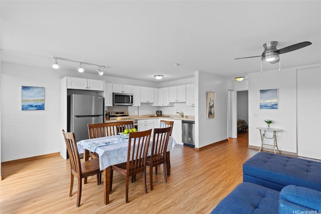 dining area featuring light wood finished floors, track lighting, and a ceiling fan