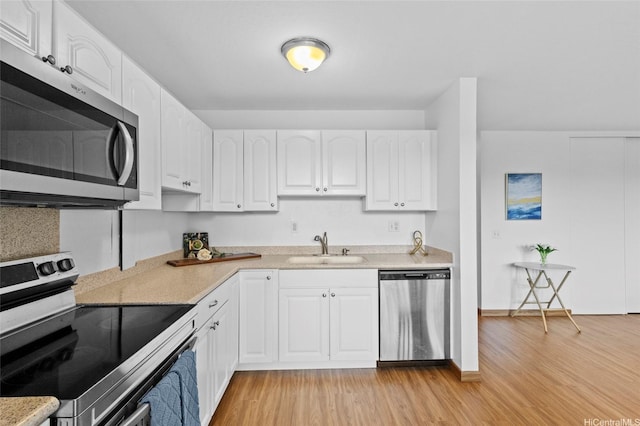 kitchen featuring light wood-type flooring, white cabinetry, appliances with stainless steel finishes, and a sink
