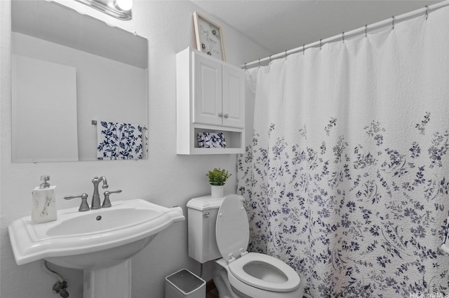 bathroom featuring a sink, toilet, and a shower with curtain