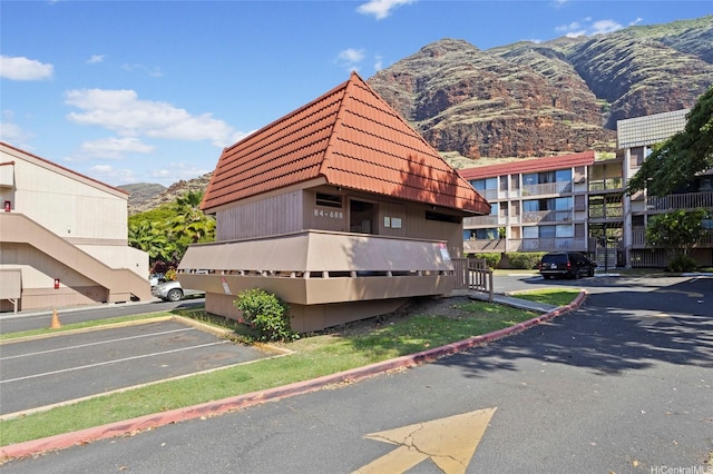 view of building exterior with uncovered parking and a mountain view