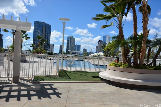 view of swimming pool featuring fence and a city view