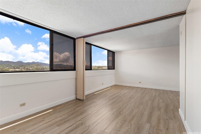 99-015 Kalaloa St Unit 803, Aiea, HI 96701 - empty room featuring a textured ceiling, light wood-type flooring, baseboards, and a mountain view