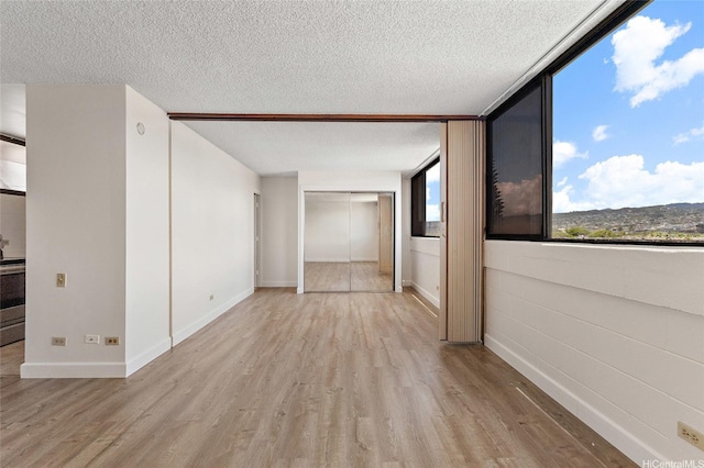 99-015 Kalaloa St Unit 803, Aiea, HI 96701 - spare room featuring light wood-type flooring, a textured ceiling, and baseboards