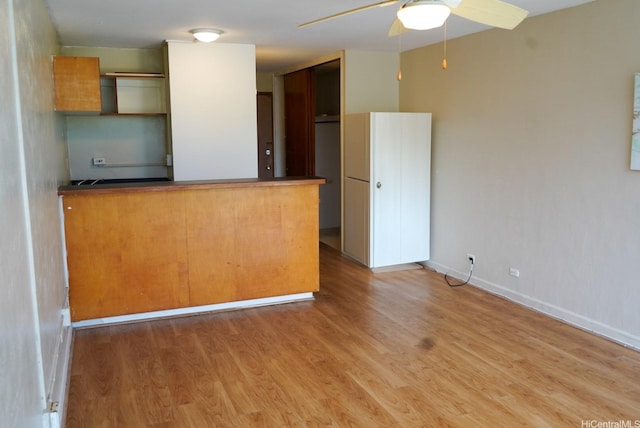 53-549 Kamehameha Hwy Unit 514, Hauula, HI 96717 - kitchen featuring a ceiling fan, a peninsula, light wood-type flooring, and dark countertops