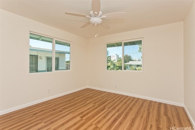 spare room with light wood finished floors, baseboards, and ceiling fan