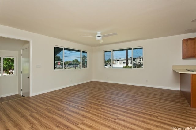 unfurnished living room featuring baseboards, ceiling fan, and light wood-style flooring