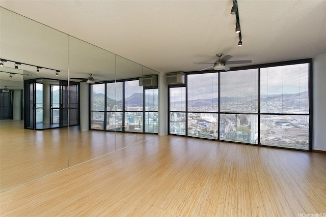 60 N Beretania St Unit 3405, Honolulu, HI 96817 - spare room featuring rail lighting, ceiling fan, wood finished floors, a wall unit AC, and a wall of windows