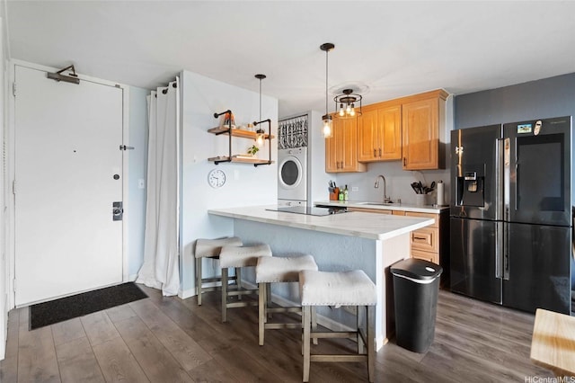 kitchen with fridge with ice dispenser, a sink, dark wood-type flooring, and light countertops
