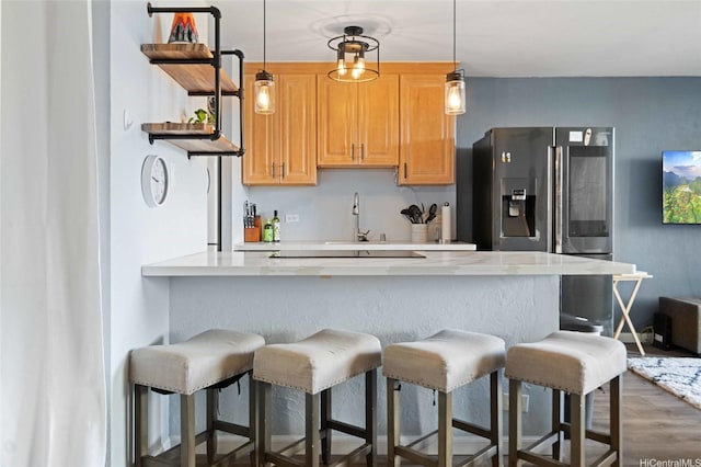 kitchen with stainless steel fridge, open shelves, a breakfast bar, and light countertops