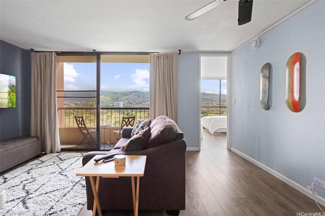 living area with baseboards, wood finished floors, floor to ceiling windows, and ceiling fan