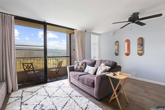 living area with wood finished floors, a ceiling fan, and baseboards
