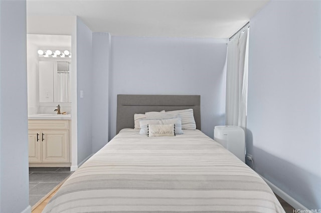 bedroom with tile patterned floors, ensuite bathroom, and a sink