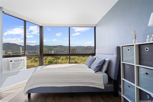 bedroom with baseboards, a textured wall, wood finished floors, and a mountain view