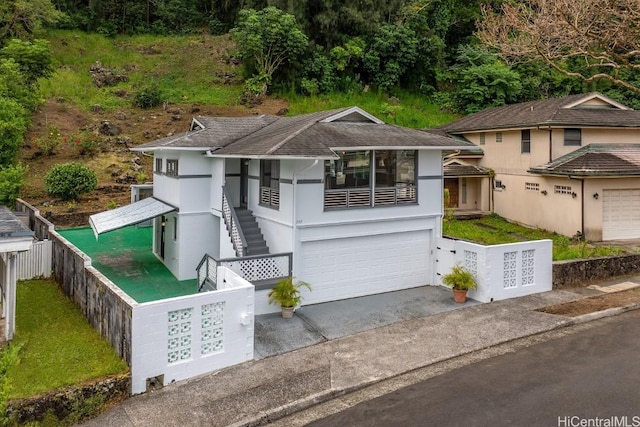 view of front facade featuring fence, stairs, an attached garage, concrete driveway, and stucco siding