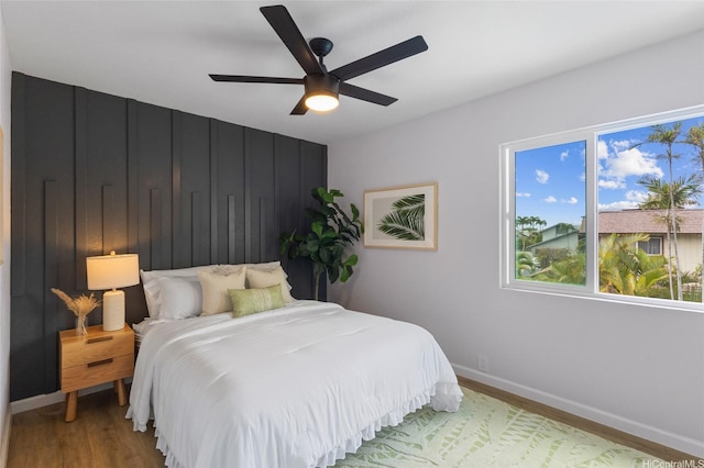 bedroom featuring wood finished floors, baseboards, and a ceiling fan