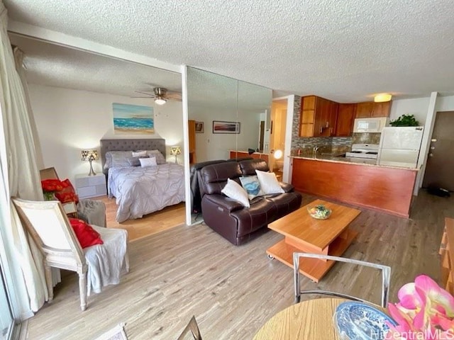 2452 Tusitala St Unit 703, Honolulu, HI 96815 - living room featuring a textured ceiling, light wood finished floors, and a ceiling fan