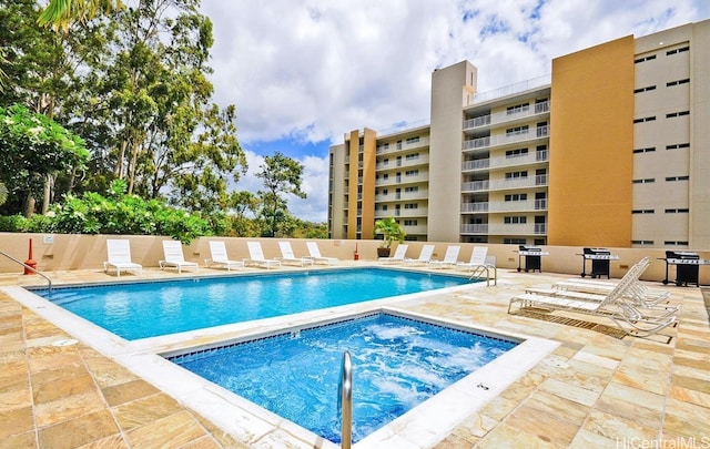 community pool with fence, a patio, and a hot tub