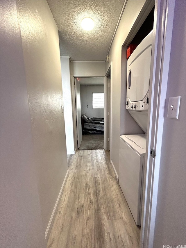corridor featuring baseboards, wood finished floors, and a textured ceiling