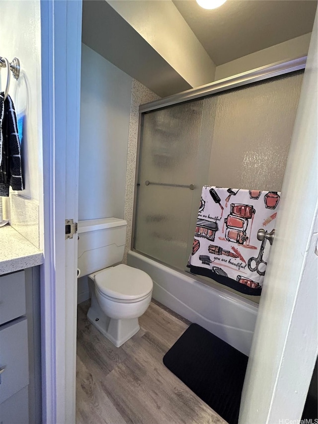 bathroom with combined bath / shower with glass door, vanity, toilet, and wood finished floors