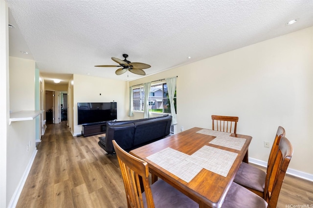 dining room with baseboards, a textured ceiling, light wood finished floors, and a ceiling fan