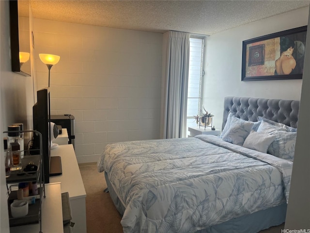 carpeted bedroom with a textured ceiling and concrete block wall