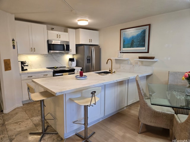 60 N Beretania St Unit 3209, Honolulu, HI 96817 - kitchen featuring appliances with stainless steel finishes, a peninsula, white cabinetry, decorative backsplash, and a breakfast bar area