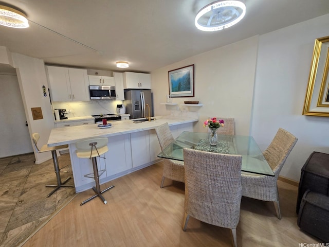60 N Beretania St Unit 3209, Honolulu, HI 96817 - kitchen featuring appliances with stainless steel finishes, a peninsula, a kitchen breakfast bar, light countertops, and light wood-style flooring