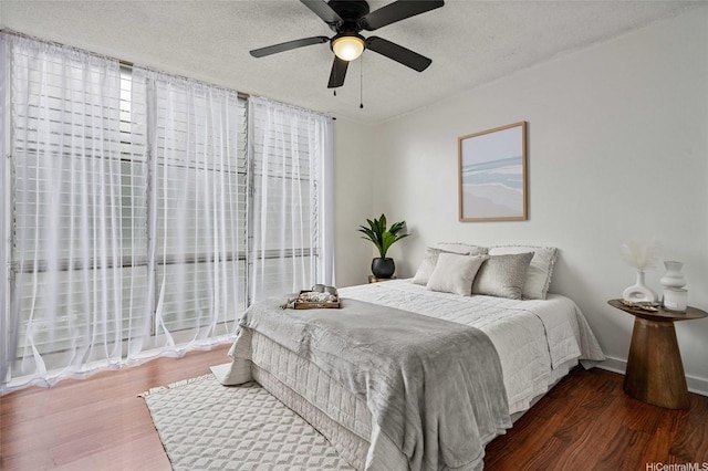 bedroom with baseboards, a ceiling fan, wood finished floors, and a textured ceiling