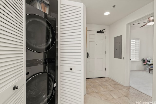 laundry room featuring electric panel, light tile patterned flooring, stacked washing maching and dryer, laundry area, and light colored carpet