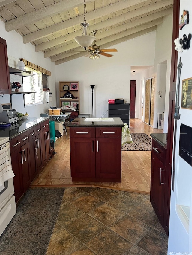 kitchen featuring vaulted ceiling with beams, reddish brown cabinets, and dark countertops