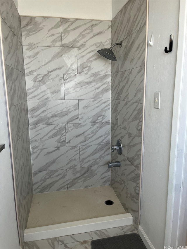 bathroom featuring marble finish floor and a tile shower