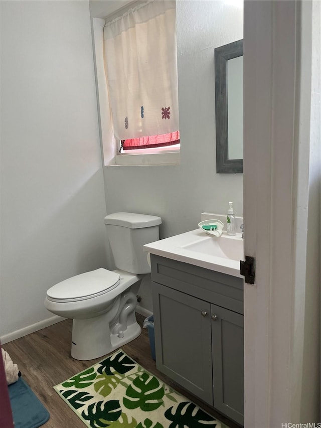 bathroom featuring toilet, vanity, wood finished floors, and baseboards