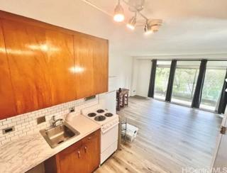 1511 Nuuanu Ave Unit 337, Honolulu, HI 96817 - kitchen featuring white range with electric cooktop, light wood-type flooring, backsplash, light countertops, and brown cabinets