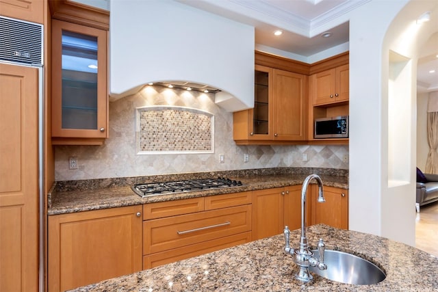 kitchen with custom exhaust hood, ornamental molding, light stone counters, appliances with stainless steel finishes, and a sink