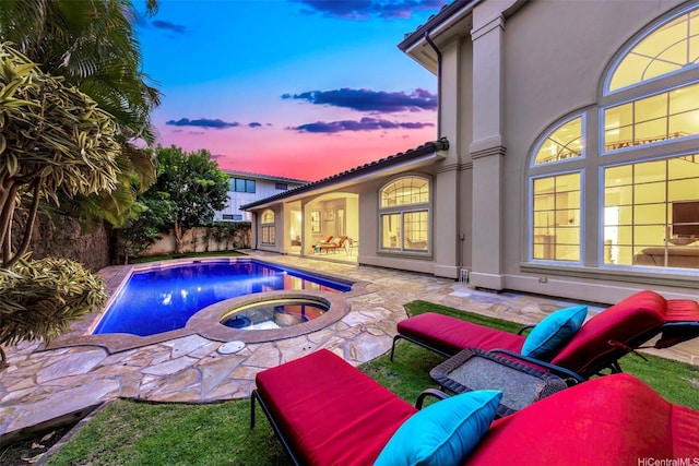 pool at dusk featuring fence, an in ground hot tub, a fenced in pool, and a patio
