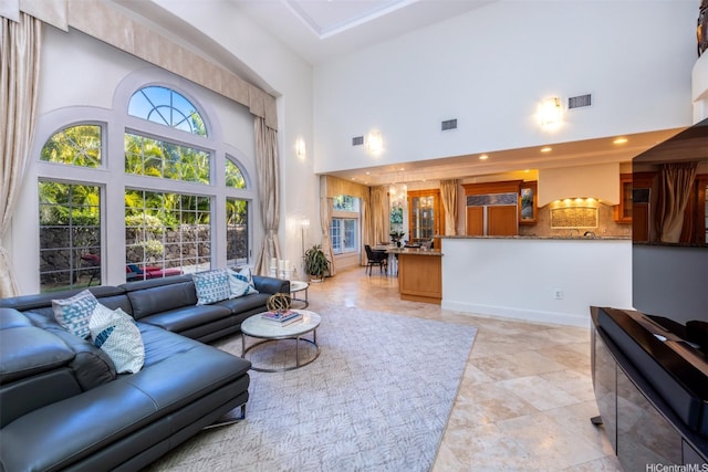 living area with recessed lighting, visible vents, and a high ceiling