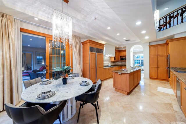 kitchen featuring an inviting chandelier, recessed lighting, appliances with stainless steel finishes, a center island with sink, and backsplash