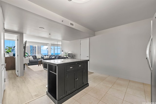 1009 Kapiolani Blvd Unit 4006, Honolulu, HI 96814 - kitchen with dark cabinets, stainless steel refrigerator, open floor plan, a kitchen island, and light countertops
