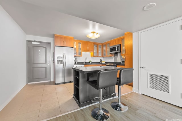 1009 Kapiolani Blvd Unit 4006, Honolulu, HI 96814 - kitchen featuring appliances with stainless steel finishes, dark countertops, glass insert cabinets, a kitchen island, and a breakfast bar area