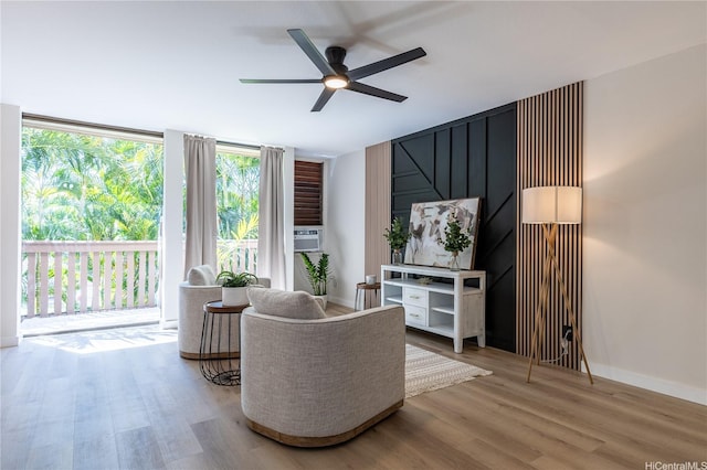 living area with baseboards, a ceiling fan, and wood finished floors