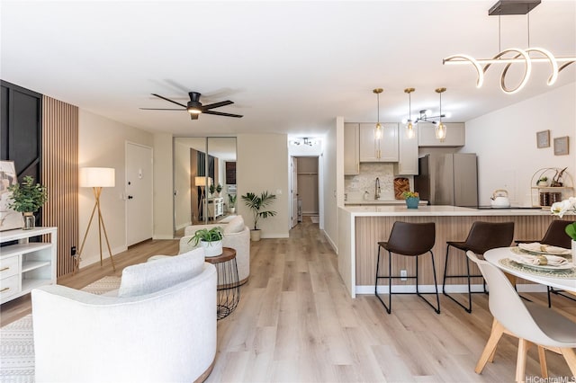 living area with light wood finished floors and ceiling fan
